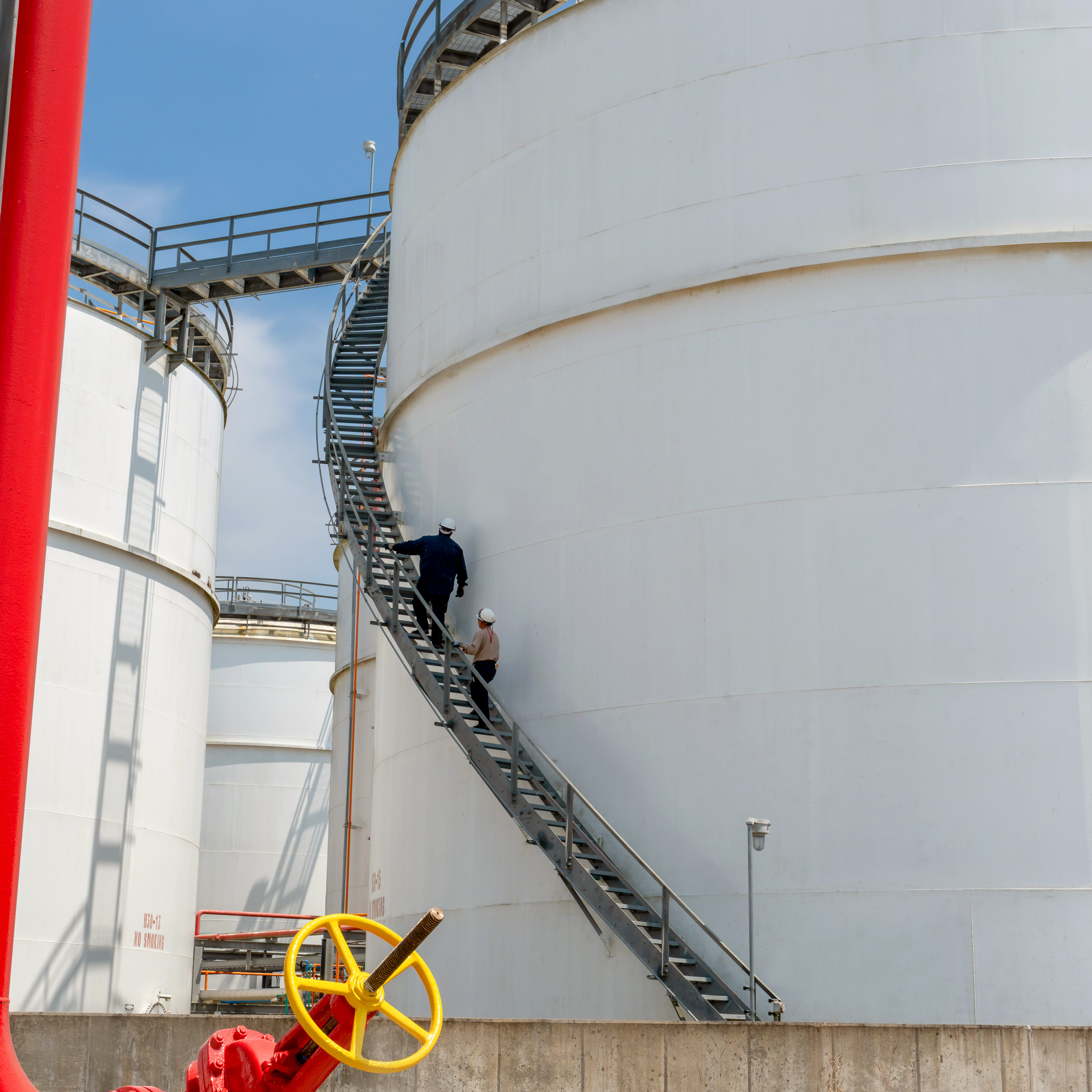 SHVN NOLA red pipe closeup workers on tank in background SHVN NOLA red pipe closeup workers on tank in background